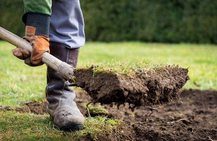 Person hebt mit Spaten Grasnarbe ab